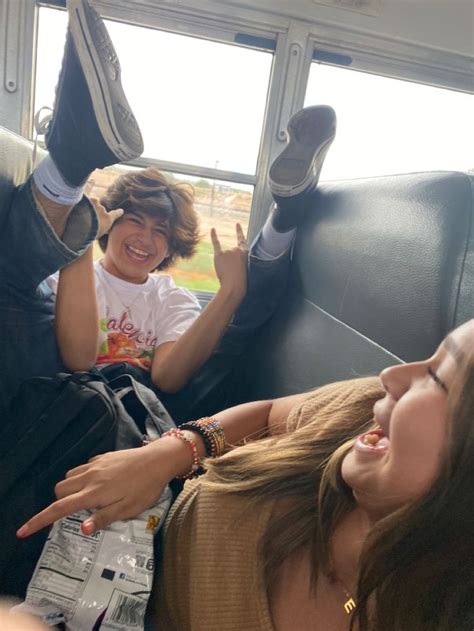 Two Girls Sitting In The Back Of A Bus With Their Feet Up And One