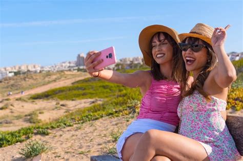 Amigas chapéu muito felizes de férias na praia tirando uma selfie