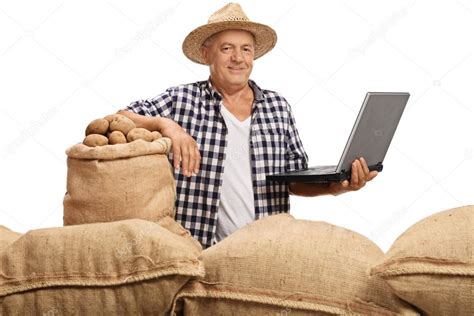 Mature Farmer Posing With Pile Of Burlap Sacks And Laptop Stock Photo