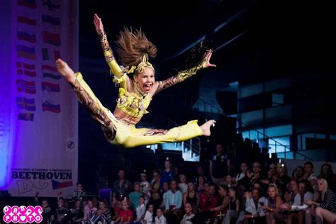 A Woman In Yellow And Black Outfit Doing A Trick On A Skateboard While