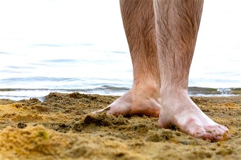 Piernas Peludas Desnudas De Un Joven Mojado De Pie En La Playa Junto Al