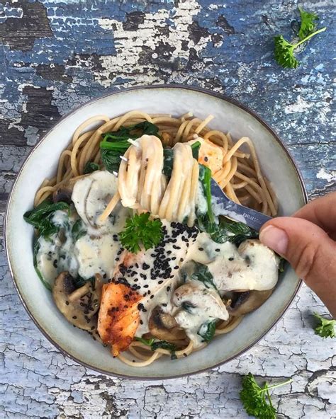 A Person Is Holding A Fork Over A Bowl Of Pasta With Chicken And Spinach