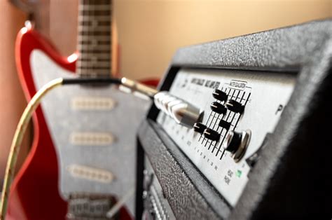 Red Electric Guitar Plugged Into Large Speaker Close Up Of Amplifier