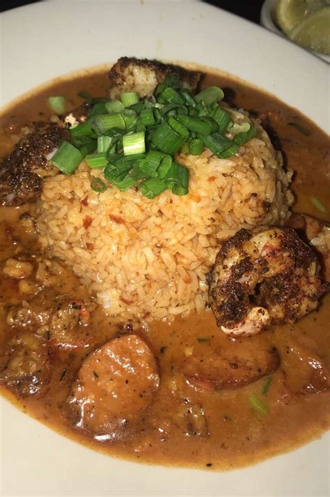 A White Plate Topped With Meat And Rice Covered In Gravy On Top Of A Table