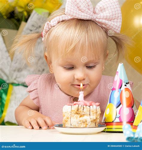 A Two Year Old Girl Blows Out A Candle On A Birthday Cake Makes A Wish