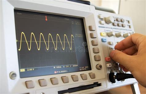 Sine wave on oscilloscope screen. And engineer's hand calibrating the ...