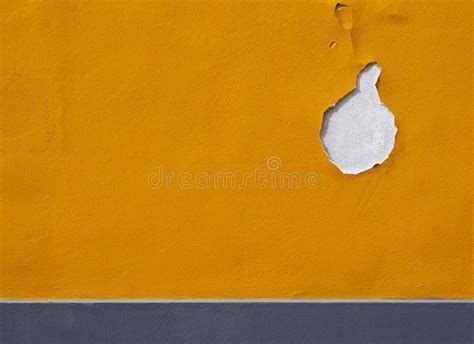 Bright Yellow Textured Paint On A Wall With Cracks And Hole Flaking