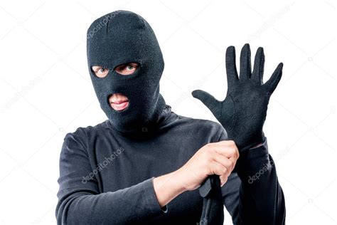 Portrait of a robber in a mask on his face straightens a glove o ...