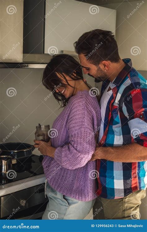 Man Holding His Smiling Wife While She Is Making Coffee Stock Image