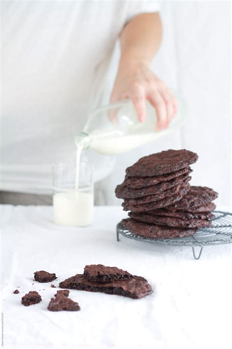 Woman Pouring Milk Behind A Stack Of Cookies By Stocksy Contributor