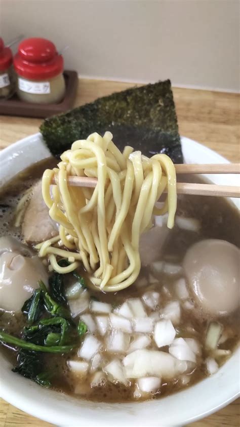 A Bowl Filled With Noodles And Vegetables On Top Of A Wooden Table Next