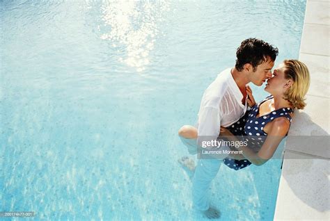 Couple Kissing In Swimming Pool Fully Clothed Elevated View Stock Photo