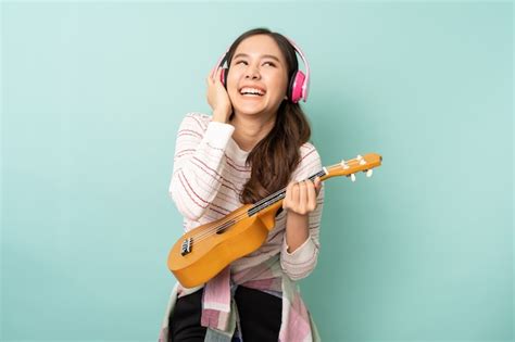 Premium Photo Young Asian Woman Using Headphones While Playing Ukulele