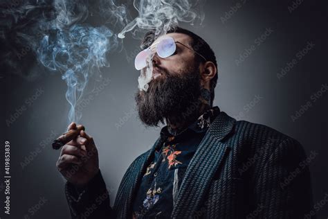 Elegant Man In Retro Style Poses In Dark Background Smoking Cigar