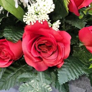 A Headstone Saddle With Red Roses And Cream Mum Grave Flowers For