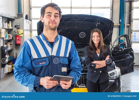 Proud Mechanic Posing In Front Of A Client With Her Car Stock Photo