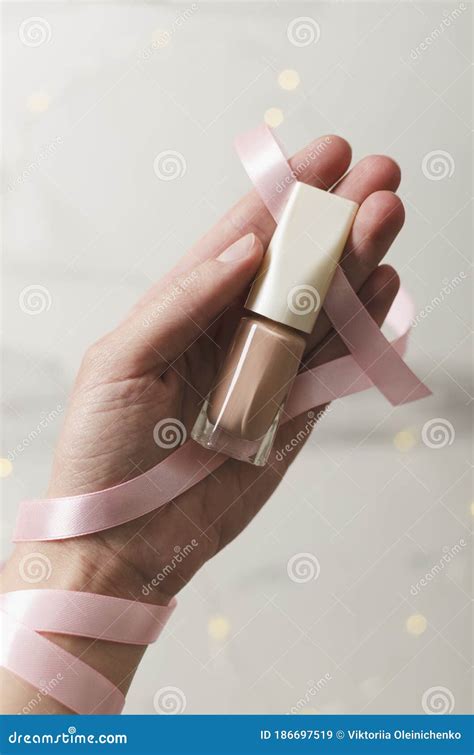 Top View Of Woman Hand Holding Nail Polish Bottle And Pink Ribbon