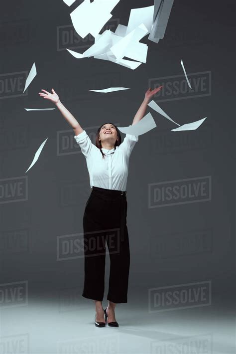 Full Length View Of Happy Young Businesswoman Throwing Papers On Grey