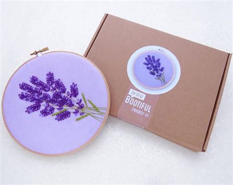 An Embroidered Lavender Flower Sits In Front Of A Box With The