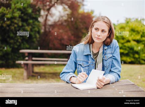 Mujer Joven Sentada En La Banqueta De Picnic En El Parque Escrito En El Bloc De Notas Fotografía