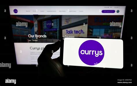 Person Holding Smartphone With Logo Of British Electronics Retail