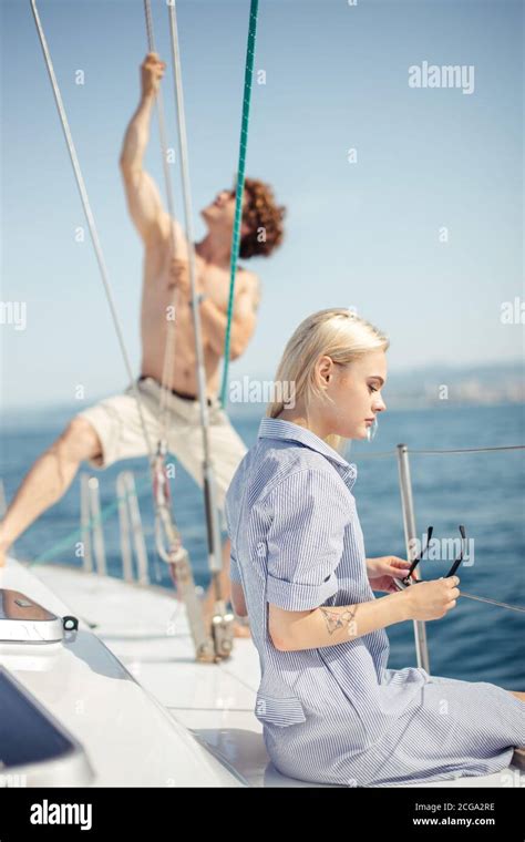 Amateur Yachtsman Sailor Pulling The Rope On Deck Of Boat Or Sailing Yacht While His Beautiful