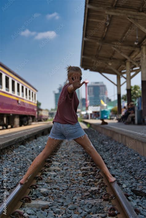 Blonde Girl Standing On A Train Track With Her Legs Spread And One Hand Raised At A Stop Sign In