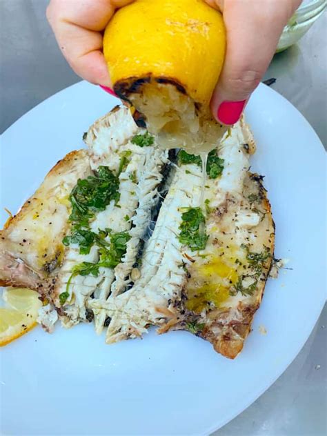 Grilled Branzino With Lemon Slices Fresh Herbs And Citrus Olive Oil