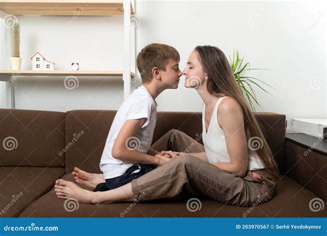 Mom And Son Rub Their Noses While Sitting On Couch At Home Close And