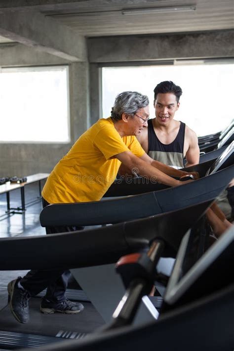 Asian Senior Man Walking Exercise On Treadmill With Personal Trainer