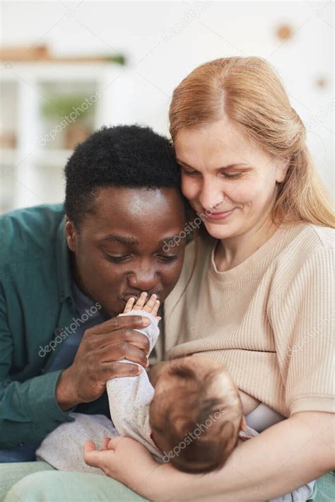 Retrato Vertical De La Feliz Familia Interracial Abrazando Al Beb