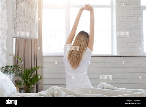 Well Rested Blonde Woman Enjoying Happy Morning Stretching In Bed