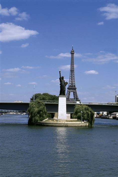 The French Statue Of Liberty On The River Seine And The Eiffel Tower In