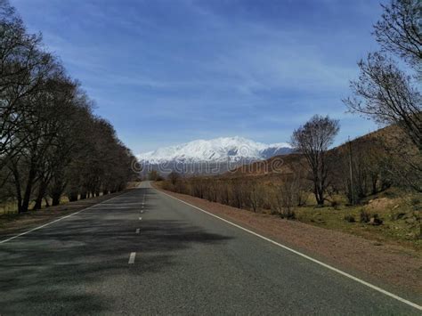 The Straight Highway Leading Towards The Snow Caps Of The Mountains