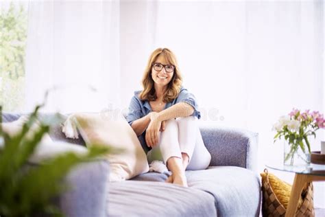 Femme D âge Moyen Souriante Se Reposant Sur Le Canapé à La Maison Image