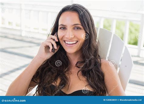 Pretty Brunette Sitting On A Chair And Calling With Her Mobile Phone