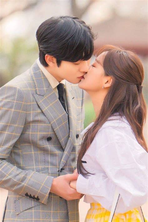 A Man And Woman Kissing Each Other In Front Of A Building