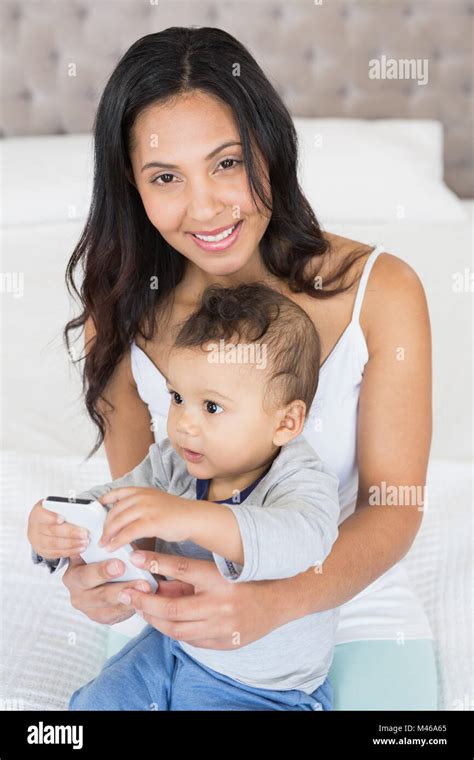 Happy Brunette Holding Her Baby And Using Smartphone Stock Photo Alamy