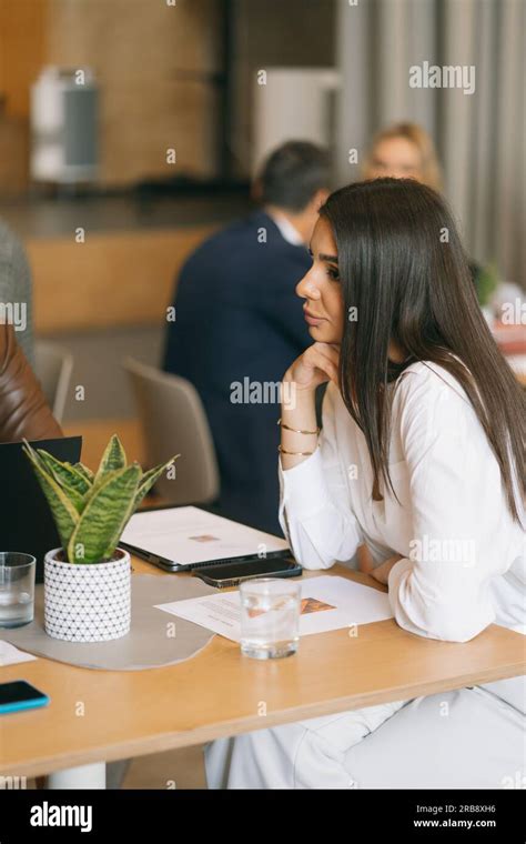 Gorgeous Brunette Business Girl Listening To Her Colleagues Having A Conversation Stock Photo