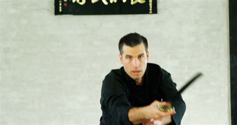 Focused Martial Artist Practicing With Sword In Traditional Dojo From