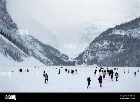 People are dwarfed against the backdrop of mountains at Lake Louise ...