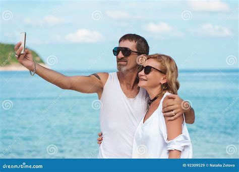 Portrait Of Mature Smiling Couple Taking A Selfie At The Beach Stock