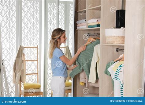 Young Woman Putting Clothes Into Wardrobe At Home Stock Image Image