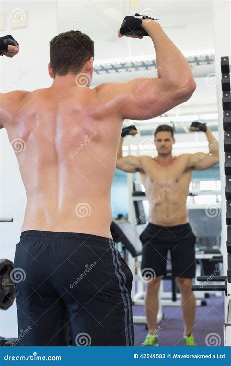 Shirtless Bodybuilder Flexing In Front Of The Mirror Stock Image