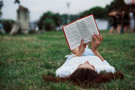 Reading some notes. Girl lying down on the green grass and have a rest ...