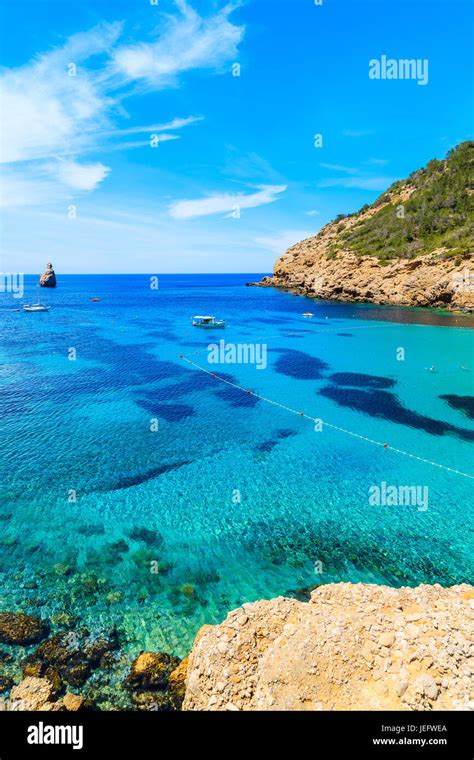 View Of Cala Benirras Bay With Fishing Boat On Azure Blue Sea Water