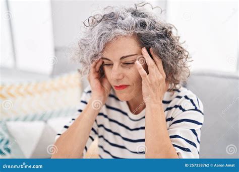 Middle Age Grey Haired Woman Suffering For Headache Sitting On Sofa At