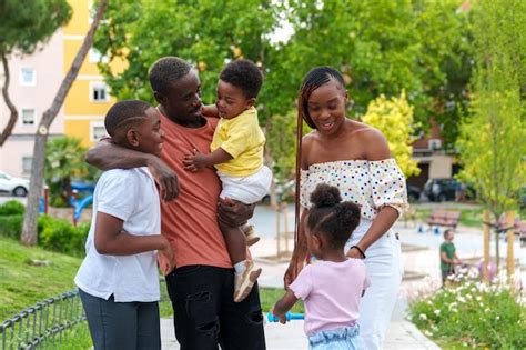 Alegre familia africana abrazando en el parque de la ciudad padre bebé