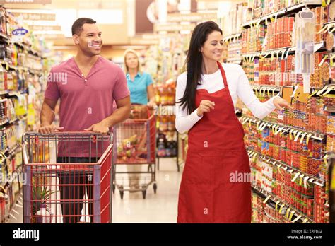 Man In Grocery Aisle Of Supermarket With Sales Assistant Stock Photo