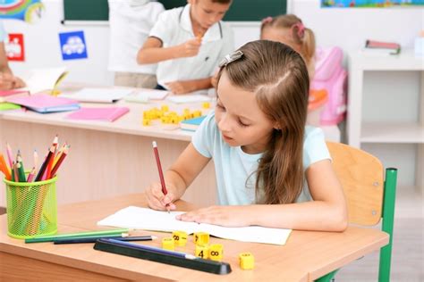 Niña dibujando en el escritorio en el aula Foto Premium